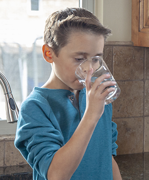 Boy drinking a glass of water.