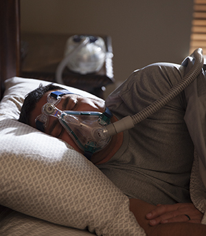 Man sleeping in bed wearing BiPAP mask.