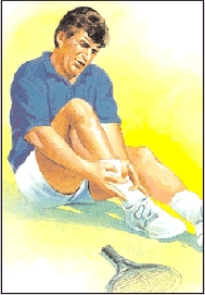 Image of man in shorts sitting next to a tennis racket holding his ankle.