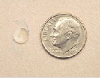 Intraocular lens next to a dime for size comparison.