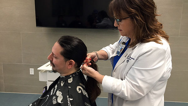 female care professional in white labcoat placing rubberband on man