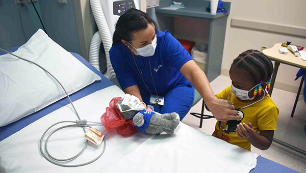 nurse lets young patient listen to her heartbeat