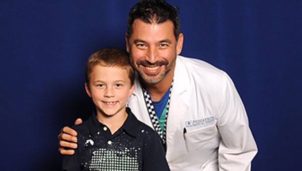 Dr. Vargas and Titan posing for a photo on a dark blue backdrop
