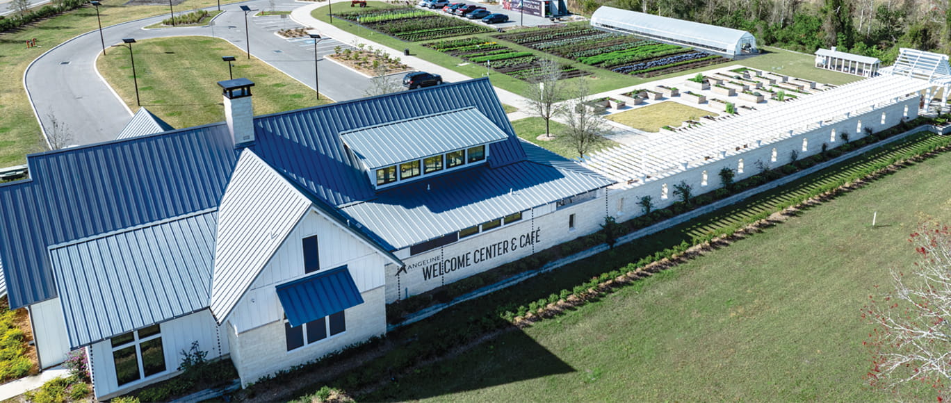 Image of the Angeline welcome center with a lot of grass and a farm in the back of the welcome center