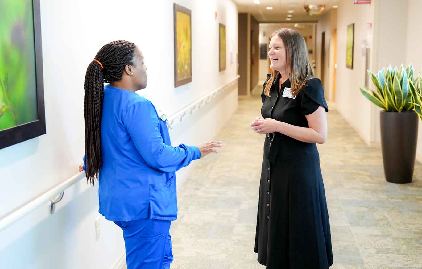 St. Joseph's Hospital North President, Sarah Dodds, communicating with a BayCare staff member in a hospital hallway.