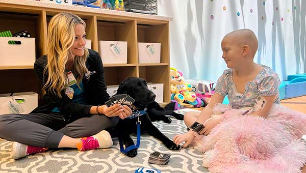 BayCare child life specialist, facility dog, and patient playing together