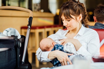 A young mother is breastfeeding her baby in a cafe.