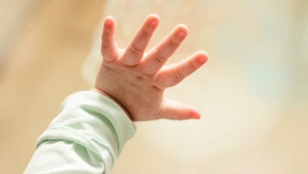Baby hand on window glass loneliness concept