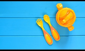 Children fork, spoon and feeding bottle on a wooden table