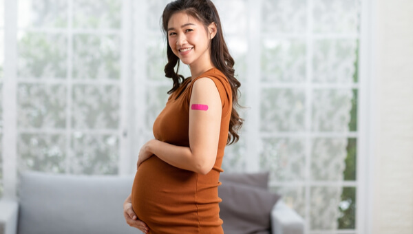 pregnant woman smiling with pink bandage on her bicep