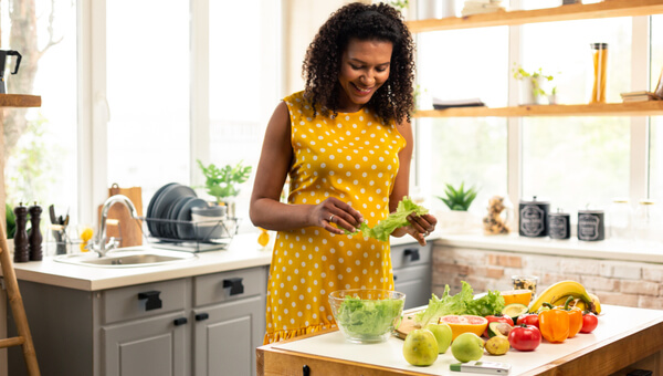 pregnant woman in yellow dress in kitchen preparing food