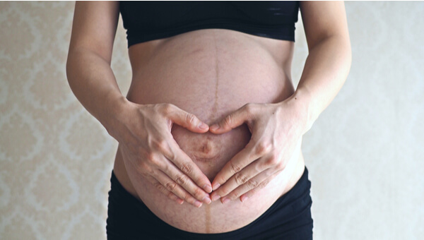 pregnant woman holding her stomach with both hands