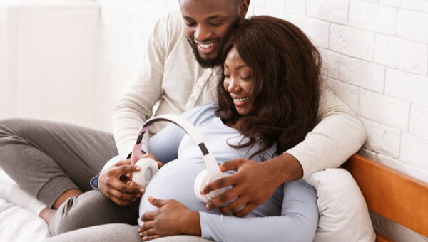 pregnant woman smiling and sitting on the couch with her husband