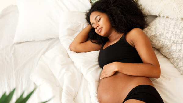 a pregnant woman laying in bed relaxing
