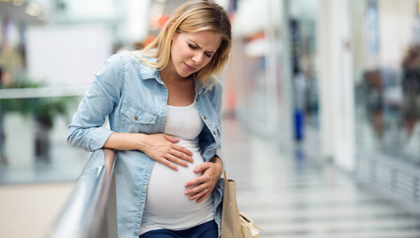 a pregnant woman on the sidewalk holding her stomach