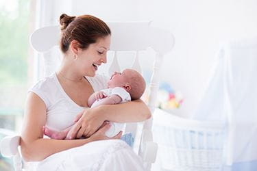 handling your newborn A new mom holds her baby while sitting in a rocking chair