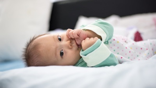 beautiful newborn baby girl is laying down sucking her thumb