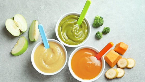 Bowls with baby food on grey background