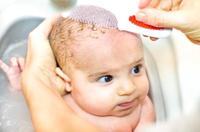 A mom combs her baby's hair after a bath.