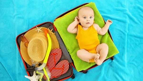 Cute baby and things for vacation in suitcase