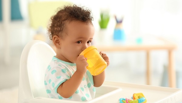 Cute baby drinking water indoors