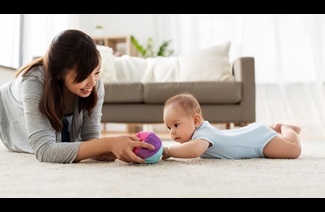 family and motherhood concept - happy mother and baby son playing with ball at home