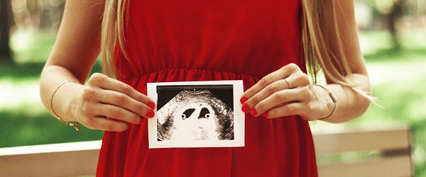first trimester woman in red dress holding photo