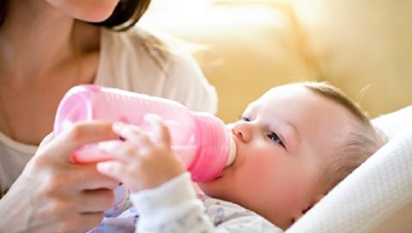 happy mother feeds the baby bottle