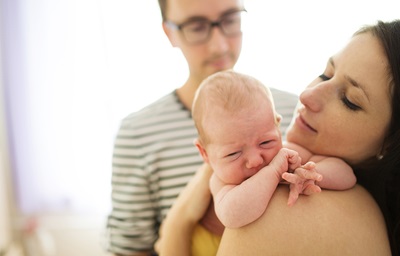 Happy young parents with their crying newborn baby girl at home
