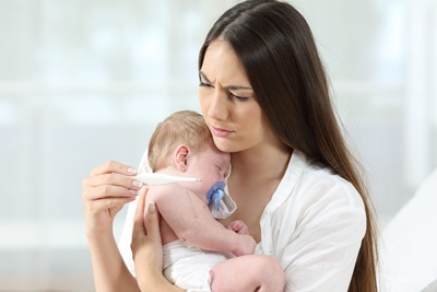 Young Mother Holds Her Baby Boy On Her Arms And Shows Him How To Adjusts  The Temperature Of The Household On A Thermostat In The Kitchen High-Res  Stock Photo - Getty Images