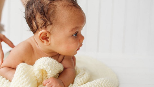 Newborn baby on stomach looking aside free space on white Adorable little child