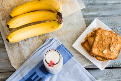 A table with toasted bread, a glass of milk and bananas