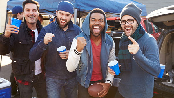 A group of male friends are tailgating before a football game