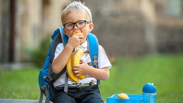 A little boy is eating his lunch at school.