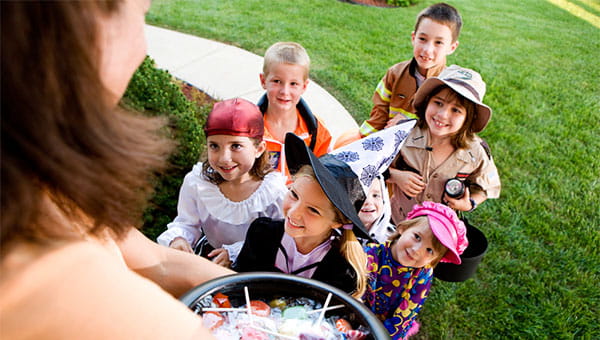 A group of costumed children is going trick-or-treating in a neighborhood