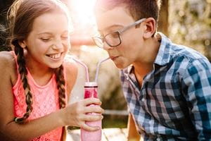 two kids drinking from the same bottle