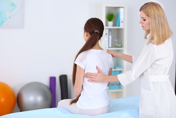 physician checking a child for scoliosis