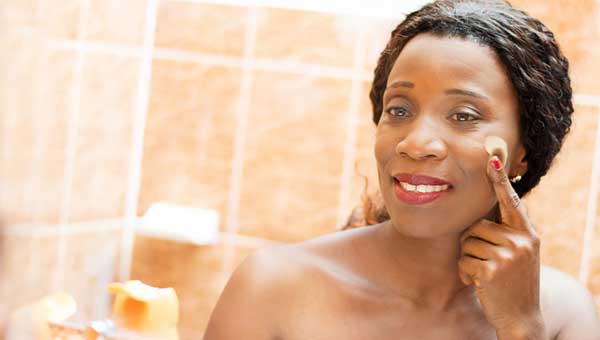 A woman is putting moisturizer on her face.