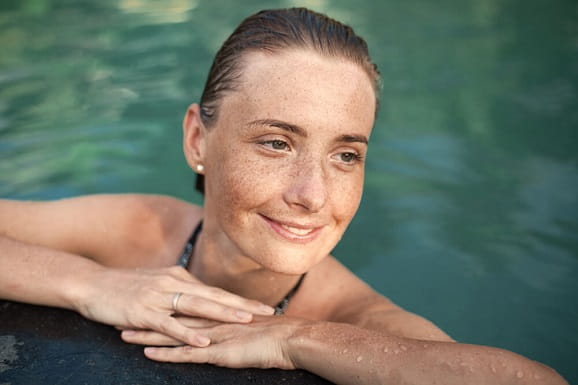A woman with sunspots is swimming at a pool
