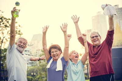 A group of seniors celebrates after exercising outdoors.