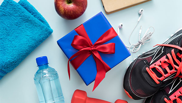 A selection of fitness gifts, including running shoes, earphones, water bottle, towel and apple.