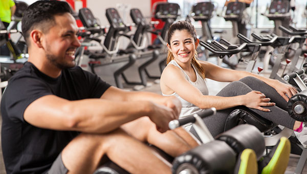 A young woman and man are doing leg exercises at the fitness center.