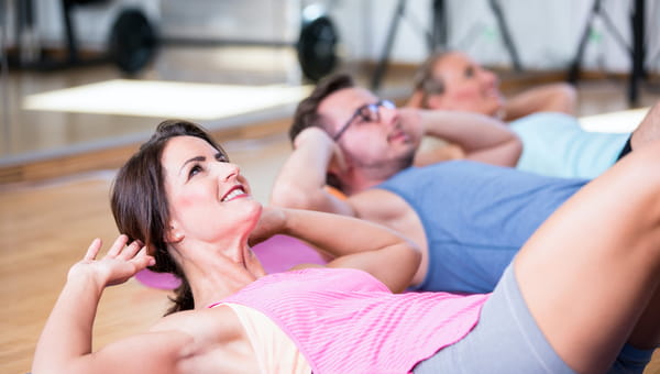 youngwomen and man are doing some situps, pushups and core exercises on a mat