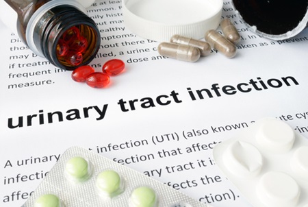 Medication is placed on top of a urinary tract infection fact sheet.