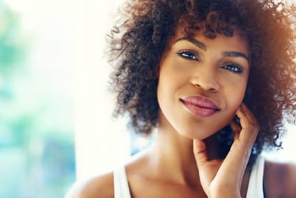 Woman looking straight ahead touching her face