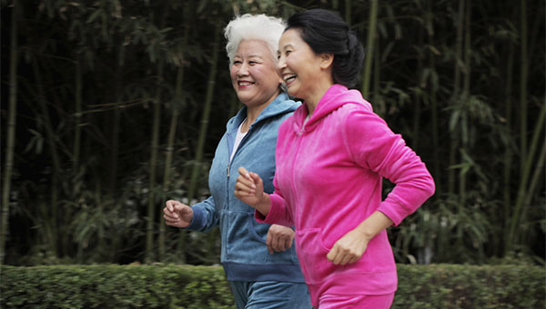 Two senior women are walking outdoors for exercise.