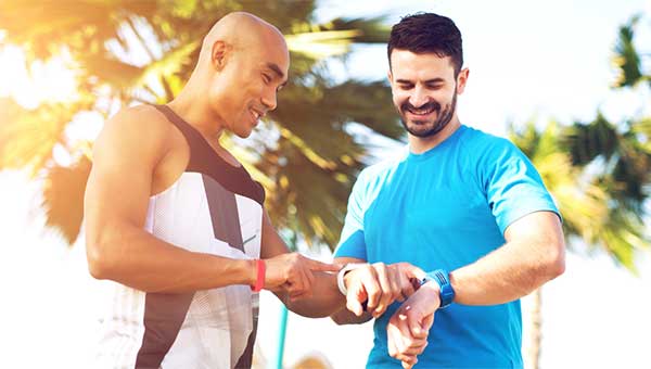 Two men check their heart rates after exercising.