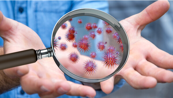 Close up on a sick man hand through magnifying glass transmitting virus