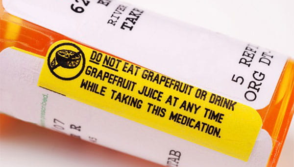 medication bottle with yellow warning label advising against eating grapefruit with medication