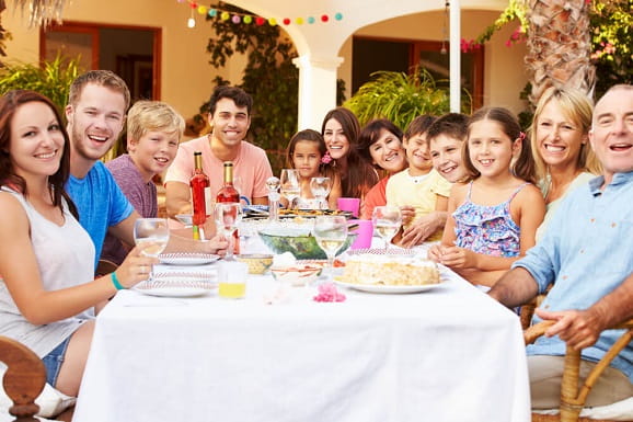 Three generations of a large family are having a meal together.